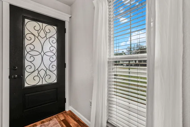 a view of an empty room with wooden floor fireplace and a window