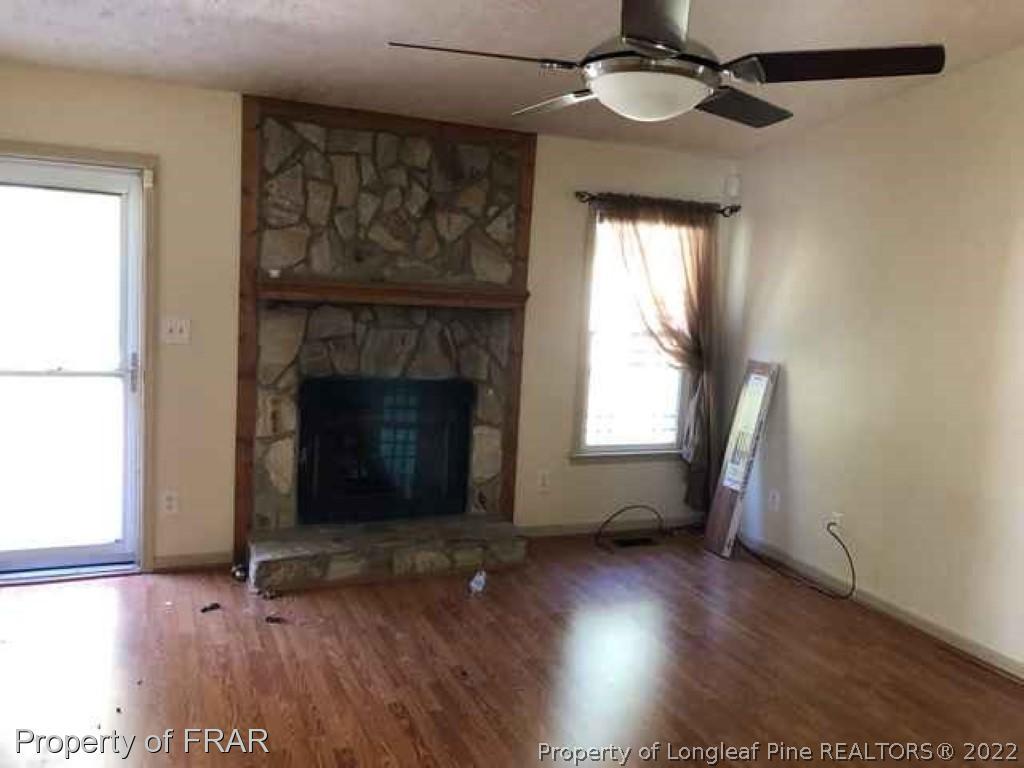 6516 Applewhite Road Fayetteville, NC 28304 - Photo 9 of 12 an empty room with wooden floor a fireplace and windows