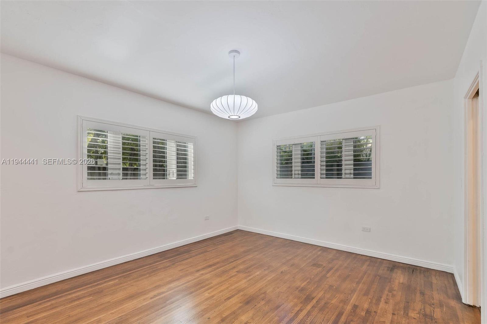 680 Northeast 57th Street Miami, FL 33137 - Photo 21 of 42 a view of an empty room with wooden floor and a window