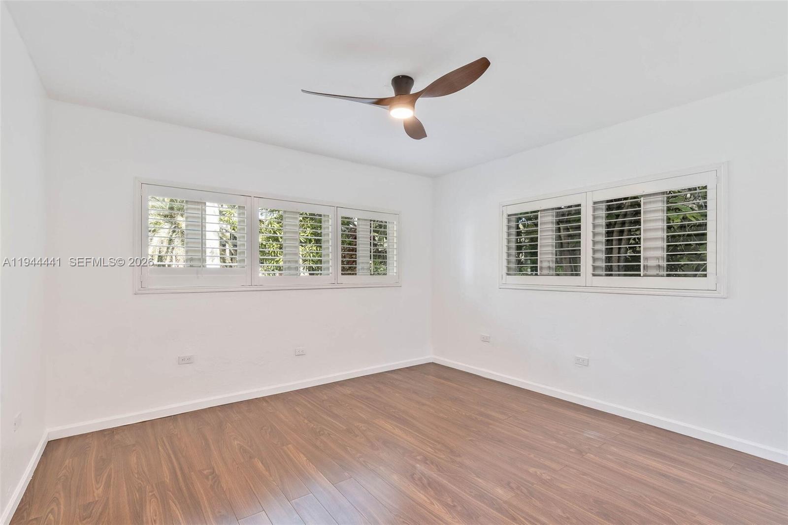 680 Northeast 57th Street Miami, FL 33137 - Photo 10 of 42 a view of an empty room with wooden floor and a window