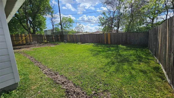 a view of a backyard with large trees and wooden fence