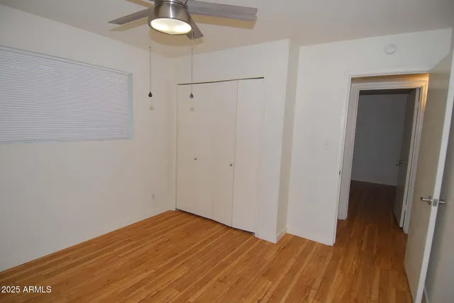 a view of empty room with wooden floor and fan