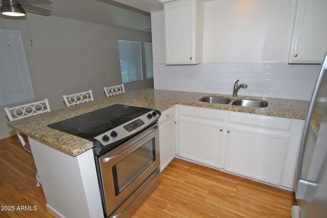 a kitchen with granite countertop a sink stove and cabinets