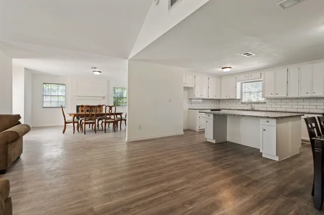 a kitchen with stainless steel appliances granite countertop a stove top oven a sink dishwasher and white cabinets with wooden floor