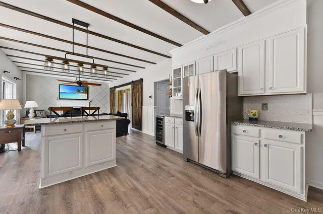 a kitchen with stainless steel appliances granite countertop a sink a stove a refrigerator cabinets and a dining table