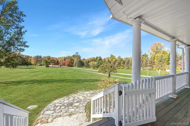 a view of a deck and yard with large tree