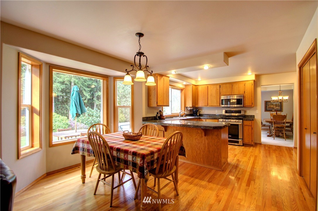 18898 Cascade Ridge Court Mount Vernon, WA 98274 - Photo 14 of 25 a dining room with stainless steel appliances granite countertop a stove top oven a dining table and chairs with wooden floor