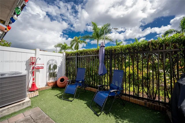a view of a chairs and table in backyard with wooden fence
