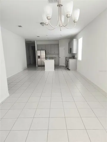 a large room with a chandelier and kitchen view