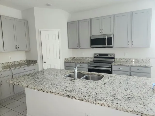 a kitchen with stainless steel appliances granite countertop a stove a sink and a microwave