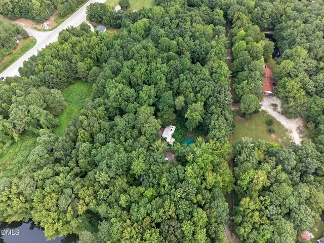 an aerial view of residential house with outdoor space and trees all around