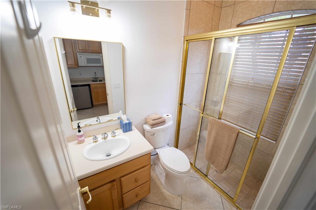 5886 Paradise Circle Naples, FL 34110 - Photo 14 of 19 Bathroom featuring tile patterned floors, a shower with door, vanity, and toilet