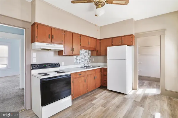 a kitchen with stainless steel appliances granite countertop a refrigerator a sink dishwasher a stove and white countertops with wooden floor