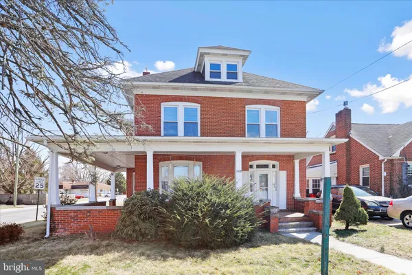 a front view of a building with garden and parking