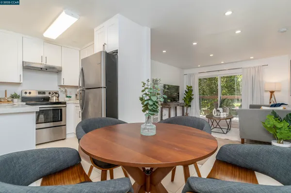 a kitchen with stainless steel appliances granite countertop a dining table chairs and refrigerator