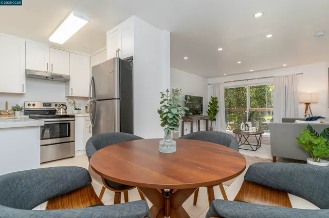 a kitchen with stainless steel appliances granite countertop a dining table chairs and refrigerator