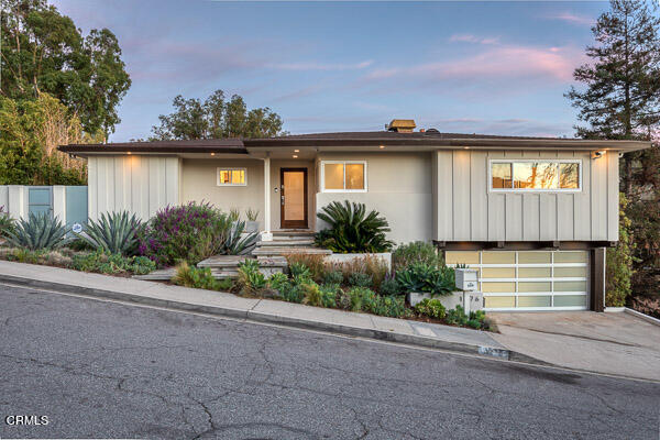 a front view of a house with a yard and potted plants
