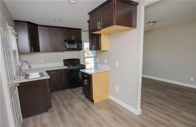 a kitchen with a sink a stove top oven a refrigerator and wooden floor