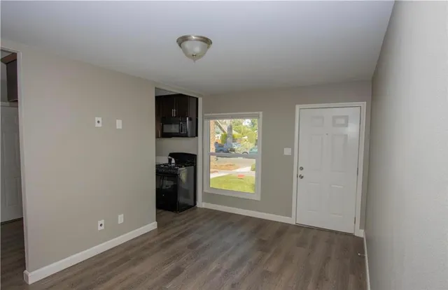 a view of an empty room with a window and wooden floor