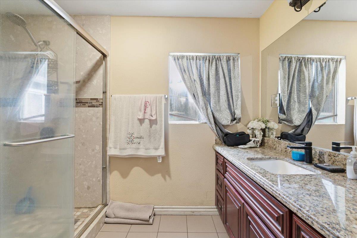 3902 Arch Road Stockton, CA 95215 - Photo 15 of 30 a bathroom with a granite countertop sink a mirror and a shower