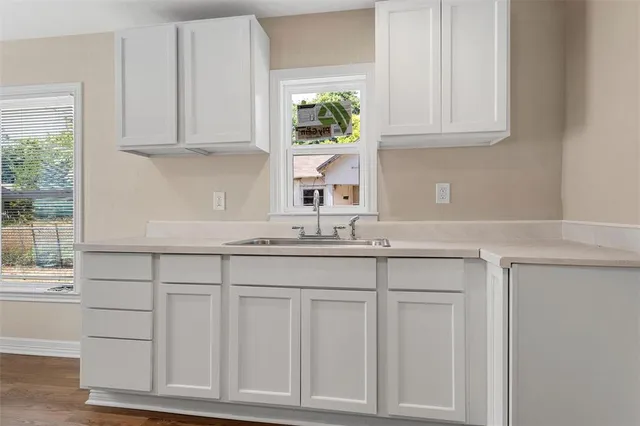 a kitchen with white cabinets and a window