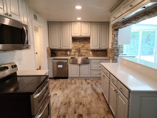 a kitchen with a sink stove top oven and cabinets