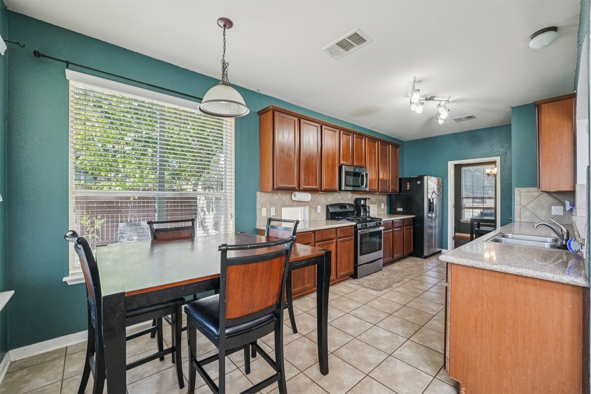 2301 Ambling Trail Pflugerville, TX 78660 - Photo 8 of 34 a kitchen with granite countertop a stove a sink dishwasher a dining table and chairs with wooden floor