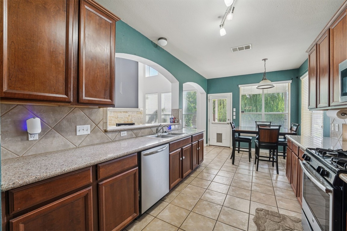 2301 Ambling Trail Pflugerville, TX 78660 - Photo 9 of 34 a kitchen with stainless steel appliances granite countertop a stove a sink and a refrigerator