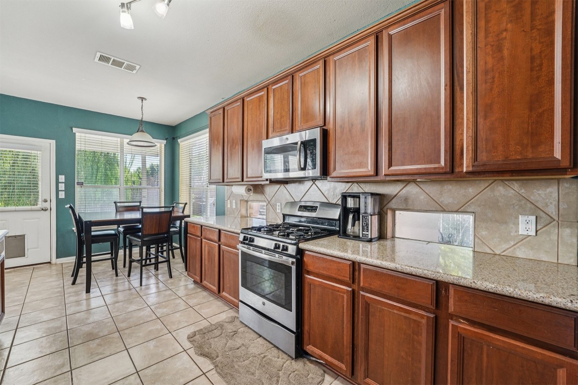 2301 Ambling Trail Pflugerville, TX 78660 - Photo 10 of 34 a kitchen with stainless steel appliances granite countertop wooden cabinets a stove top oven a sink and dishwasher