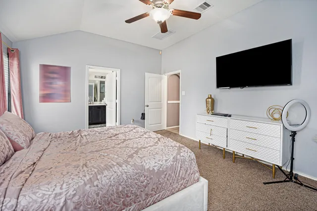 a bedroom with a bed flat screen tv and a chandelier