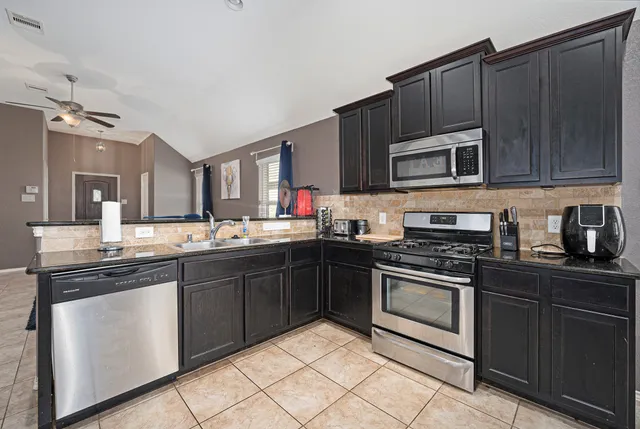a kitchen with stainless steel appliances granite countertop a stove top oven a sink dishwasher and cabinets