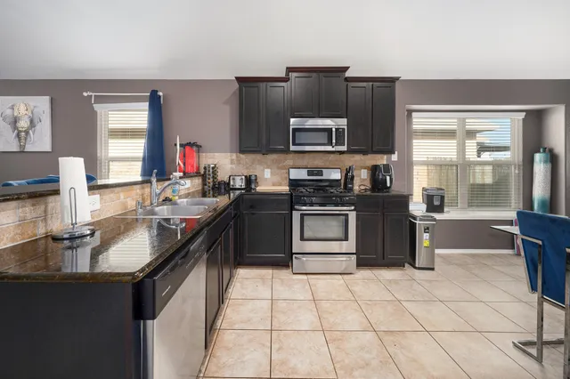 a kitchen with stainless steel appliances granite countertop a sink stove and refrigerator