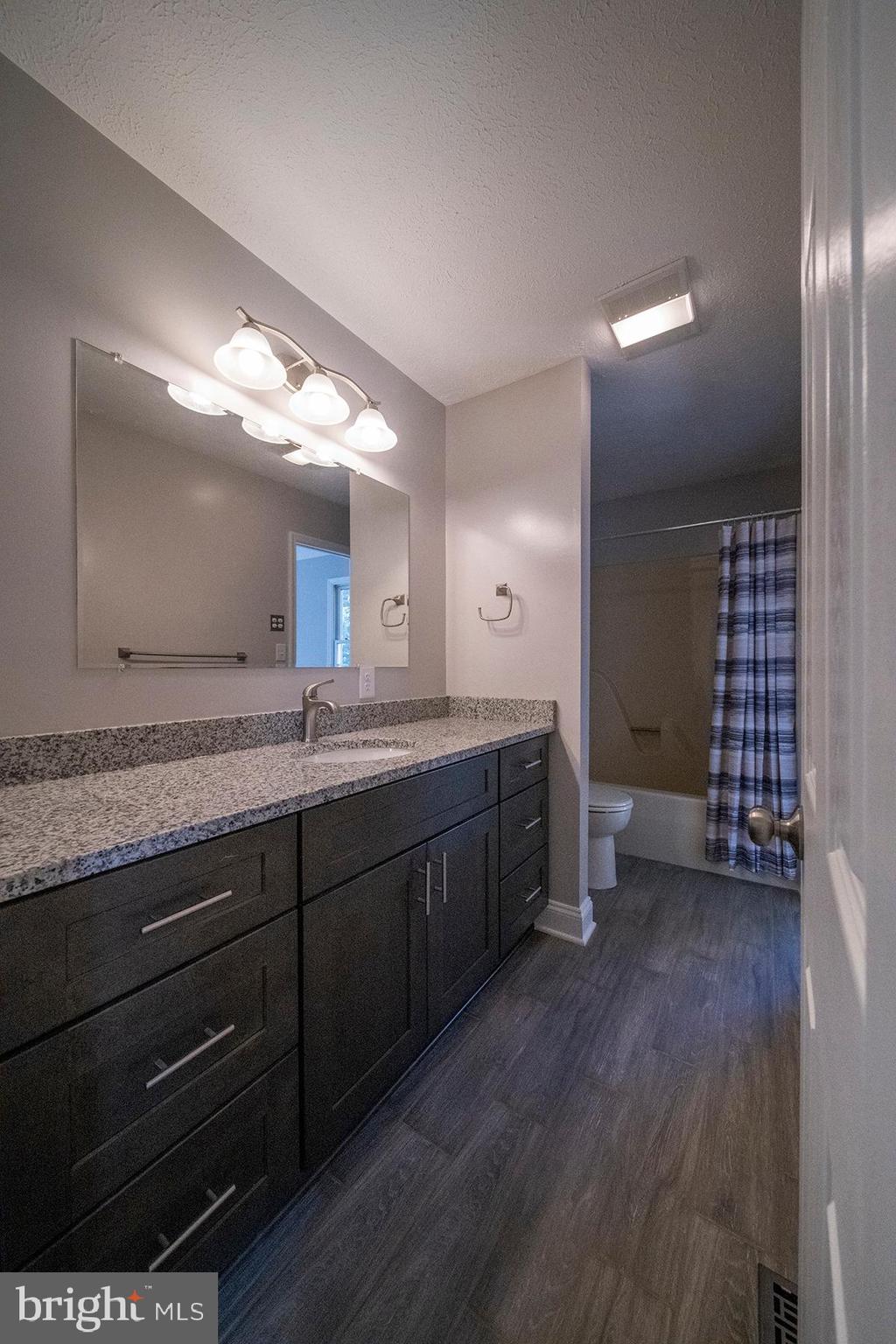 345 Edgewood Road Linthicum Heights, MD 21090 - Photo 26 of 63 a spacious bathroom with a granite countertop sink and a mirror