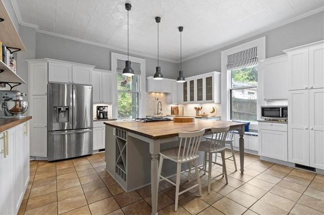 a kitchen with kitchen island granite countertop a stove a refrigerator a oven a sink a dining table and chairs with wooden floor