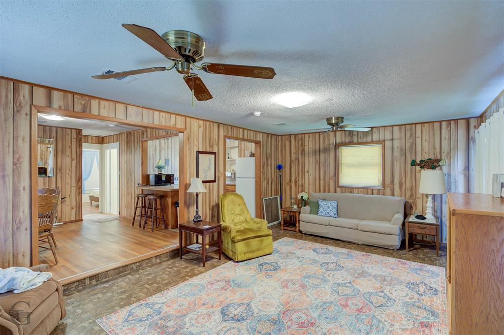 1366 United Gas Road Ringgold, LA 71068 - Photo 14 of 19 Living area featuring a textured ceiling, a ceiling fan, wood finished floors, and wood walls