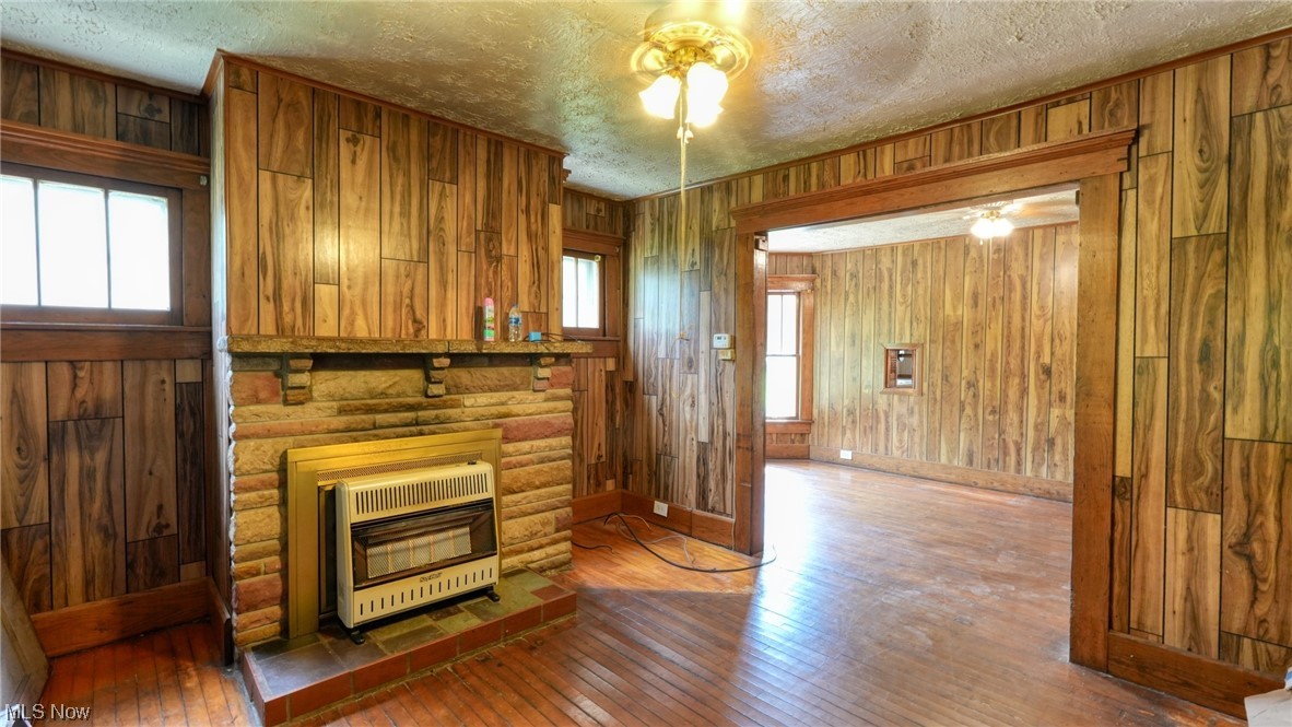 40862 Rado Ridge Road Caldwell, OH 43724 - Photo 2 of 35 Hardwood floored living room featuring log walls, a fireplace, and a textured ceiling