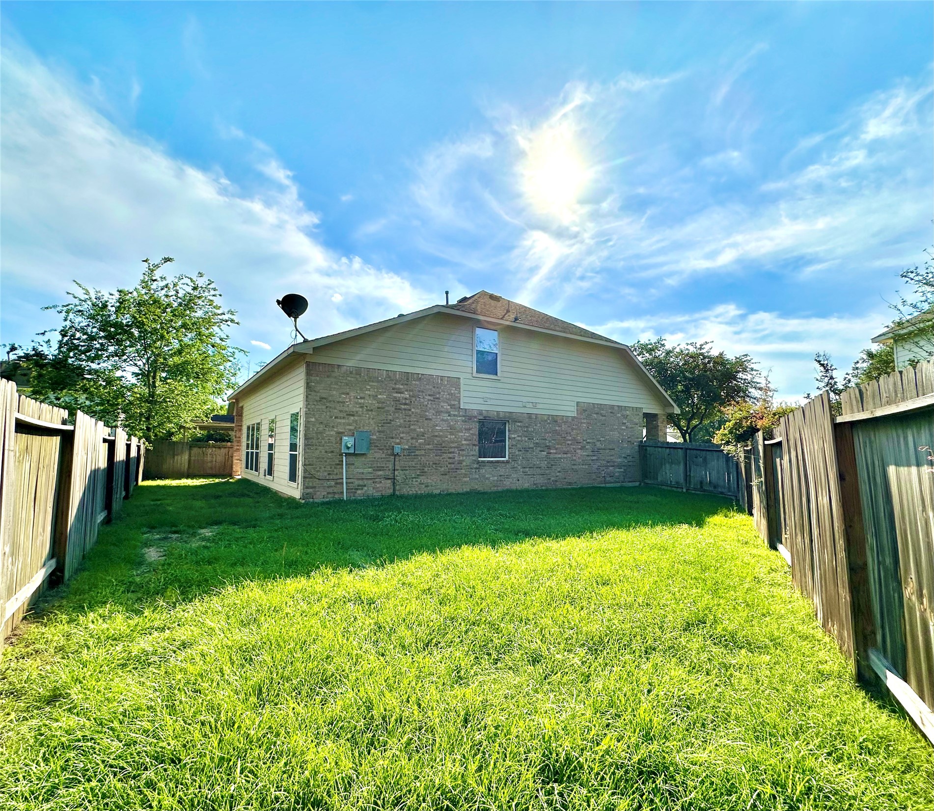 9611 Babbling Spring Court Tomball, TX 77375 - Photo 29 of 31 A spacious backyard with a well-maintained lawn, enclosed by wooden fencing, perfect for outdoor activities. The house features a brick exterior and multiple windows, providing plenty of natural light.