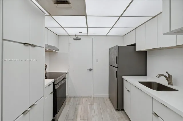 a kitchen with a sink a refrigerator and cabinets
