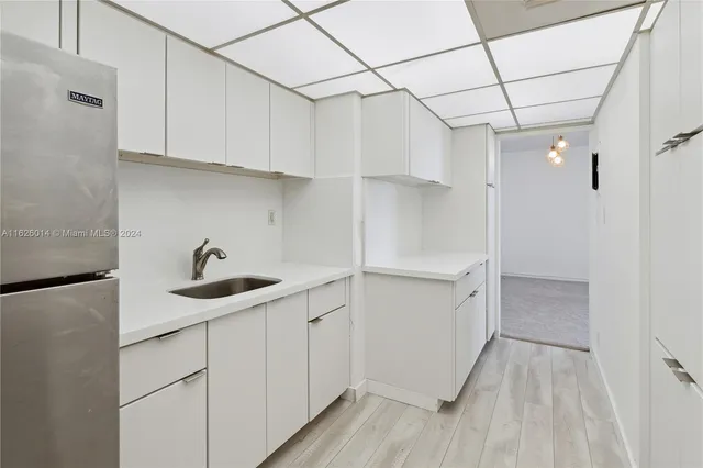a kitchen with white cabinets and wooden floor