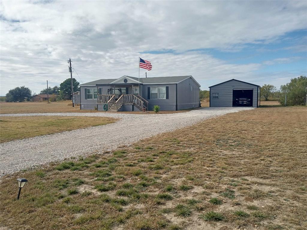 a front view of a house with a yard and mountain view in back