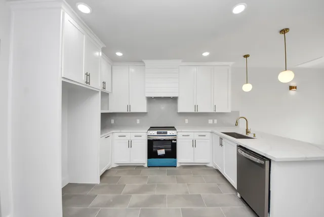 a kitchen with granite countertop white cabinets and stainless steel appliances