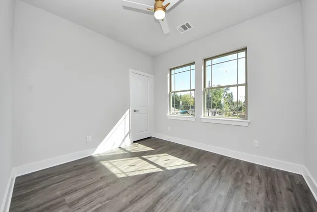 an empty room with wooden floor and windows