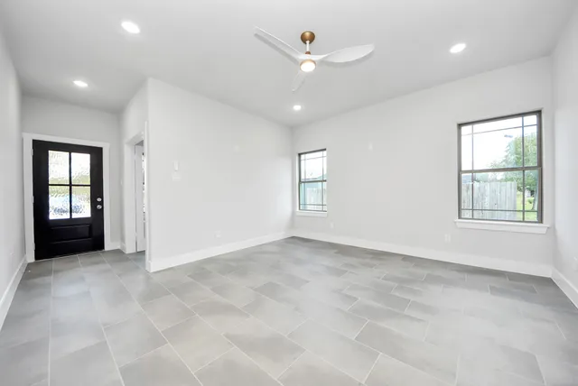 an empty room with windows and ceiling fan