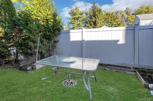 a view of a backyard with table and chairs wooden fence