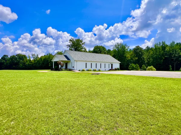 a kitchen with stainless steel appliances a stove a refrigerator a sink a dining table and chairs with wooden floor