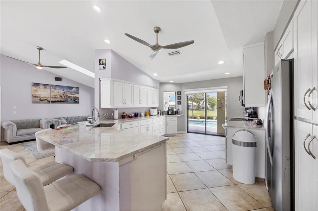 4 Leeward Drive Placida, FL 33946 - Photo 11 of 37 a open kitchen with stainless steel appliances granite countertop a refrigerator a sink dishwasher a dining table and chairs with white cabinets
