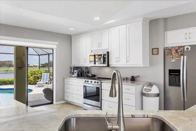 a kitchen with stainless steel appliances granite countertop a stove a refrigerator a sink a oven with a dining table and chair