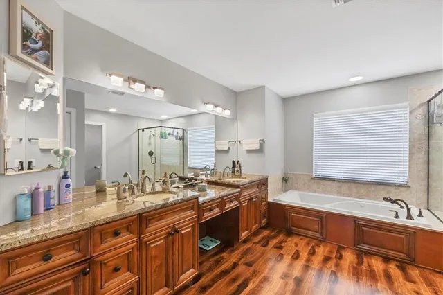 a large bathroom with a granite countertop double vanity sink a mirror and a bathtub