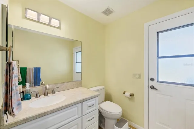 a bathroom with a granite countertop sink mirror vanity and toilet