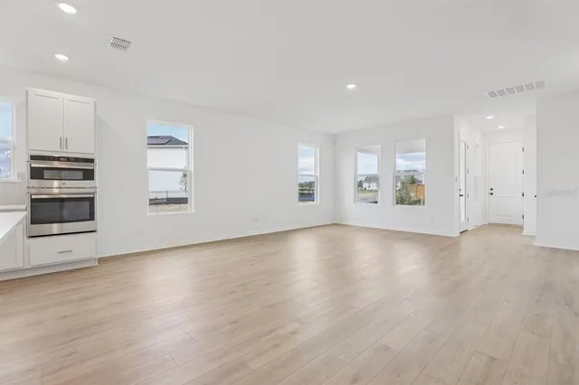 a view of an empty room with a window and wooden floor